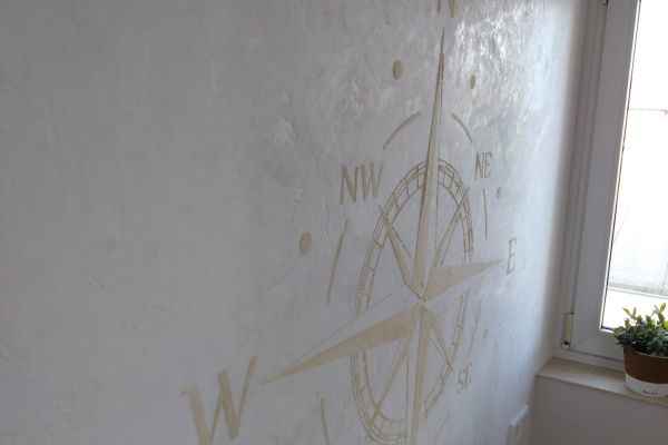 Sie sehen eine Relief mit einer Windrose auf Kalkputz
