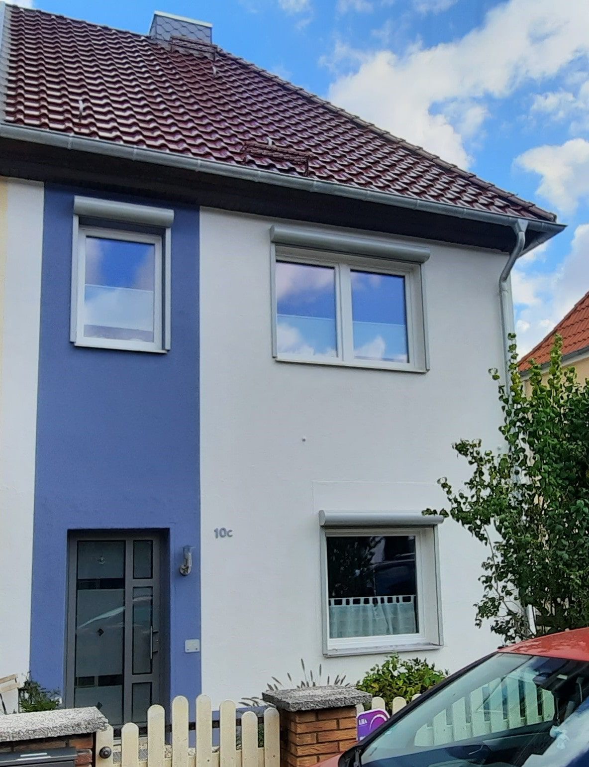 Man sieht seitlich auf eine weiße Treppe und schaut direkt auf eine rötliche Steinwand