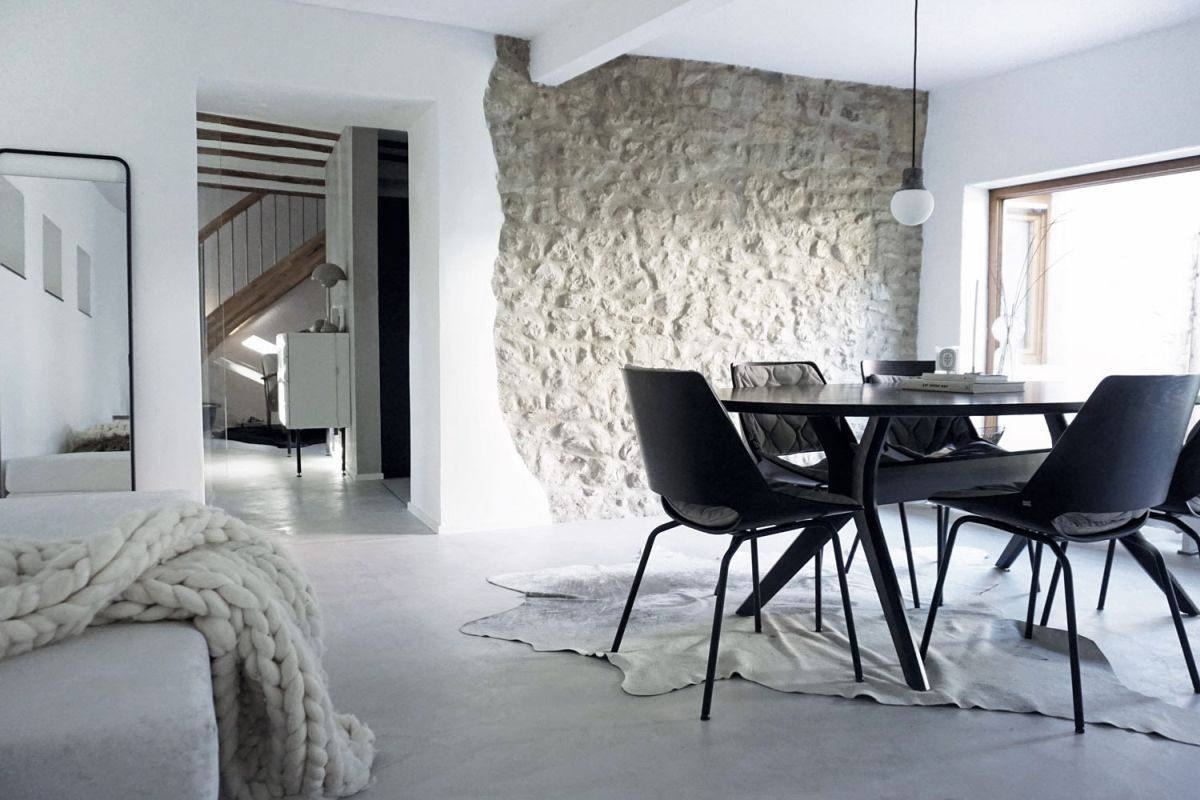 Man sieht einen wunderschön gestalteten Raum mit einem grauen Boden und akzentuierten Möbeln und Wänden