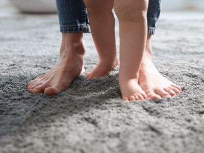 Man sieht ein paar Kinderfüße & Herrenfüße auf weichem Teppich laufen - Malermeister Marco Schubert | Wolfenbüttel